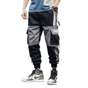 Black and grey colorblock cargo joggers on a white background, front view with flap pockets and patch