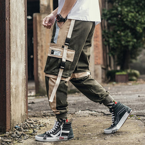Army green Colorblock Cyberpunk Pants in side view while walking, long beige strap and buckle pocket