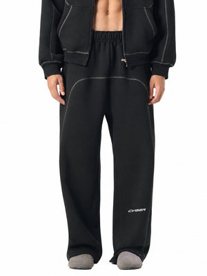 Black baggy sweatpants worn with the matching zip hoodie, front view of the white drawstring and grey stitching