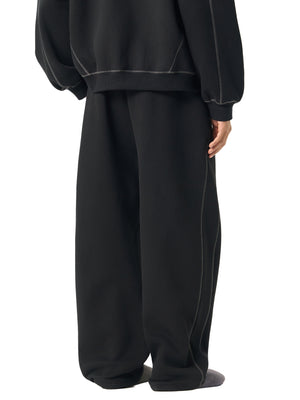 Back view of the black baggy fleece sweatpants worn with the matching hoodie, loose straight leg