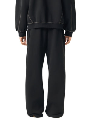 Back three-quarter view of the black sweatpants on a model, relaxed fleece leg falling to the floor