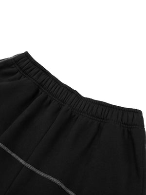 Close-up of the elastic waistband on the black sweatpants, with a grey contrast seam curving below it