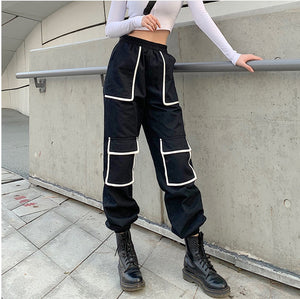 Black y2k cargo pants with white trim, front view at an angle, square patch pockets on the thigh and knee