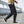 Black cropped cargo joggers in side view while walking, button flap thigh pocket and banded ankle