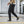 Black baggy cargo pants in side view while walking, oversized thigh pocket and elastic ankle cuff