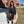 Black cropped denim jacket worn over a black bodycon midi skirt, front view by a brick pillar