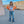 Orange cropped denim jacket with button front, front view with both hands on the hips
