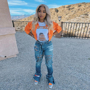 Orange cropped denim jacket with button front, front view with both hands on the hips