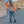 Orange short trucker jacket worn open, front view with one hand raised, ripped jeans and grey bag