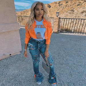 Orange coloured denim jacket with chest flap pockets, front view holding a small grey bag