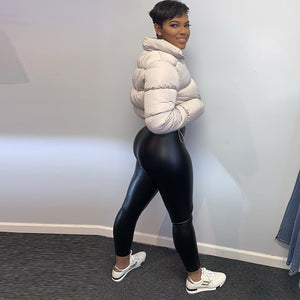 Abrikos-creme pufferjakke set fra siden, kort i taljen over sorte leggings og hvide sneakers