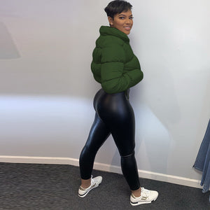 Grøn kort pufferjakke set fra siden, høj stå-op-krave og buskede ærmer med sorte leggings