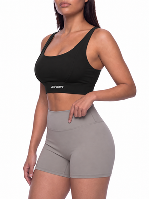Three-quarter view on the model in the black yoga bra, worn with grey high-waisted shorts
