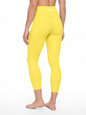 Three-quarter back view on the model in lemon yellow, the leggings ending above the ankle