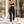 A woman walks outside in the black high waisted leggings and a black sports bra, seen from behind