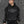 Man in a black cap wearing the Tribal Emblem Y2K Hoodie, front view of the gray thorn emblem on the chest and sleeves