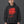 Man in a black cap wearing the Red Blur Face hoodie, front view of the blurred red portrait on washed black fleece