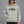 Model in white wrap sunglasses wearing the Light Gray oversized hoodie, hand in the kangaroo pocket, front view