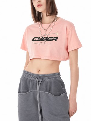 Model in the Cyber Washed Y2K Crop Top in shrimp skin powder pink, front view, black CYBER print and gray sweatpants