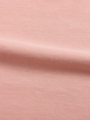 Close-up of the shrimp skin powder pink cotton in soft folds, faded surface with a fine knit texture