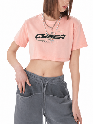 Shrimp skin powder pink washed crop top on a model with a hand in her pocket, black CYBER print and chain necklace