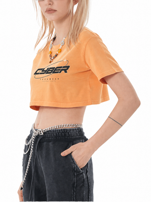 Orange colourway of the washed Y2K crop top on a model, side view with a beaded necklace and a chain belt