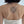 Woman's upper back in a white tank top with a black spider web temporary tattoo between the shoulder blades