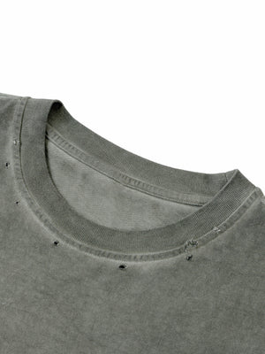 Close-up of the ribbed round neckline, distressed with small punched holes across the washed cotton