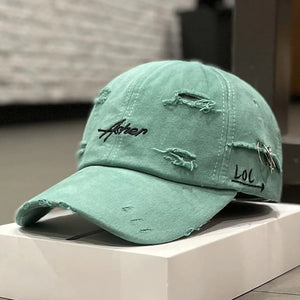 Green distressed baseball cap with script embroidery and a brim ring