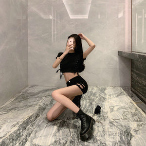 Woman kneeling in the black double buckle shorts and boots, side cut-outs and straps visible on the leg