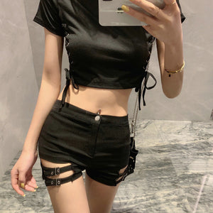 Close front view of the black high waist shorts, button waist and two buckle straps across a side cut-out