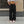 Black parachute y2k pants on a woman in front of a stone wall, front view of the baggy cargo legs and sneakers