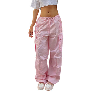 Pink baggy parachute pants on a white background, front view of the wide legs gathered at the drawstring hems