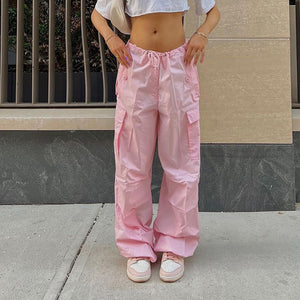 Pink Drawstring Parachute Y2K Pants worn on a street, front view, low waist, baggy legs and cargo pockets