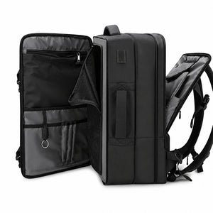 Expandable Business Techwear Backpack in black opened flat beside a laptop, notebook and daily items