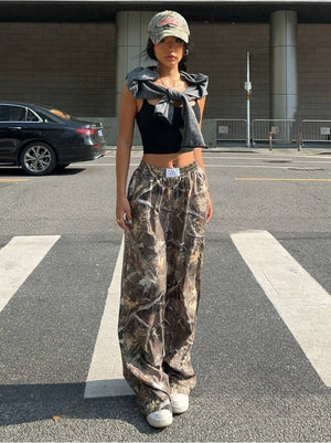Model in Forest Camo cargobroek en een pet, vooraanzicht in volle lengte, losse wijde pijp over witte sneakers