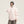Pink short parka with a fluffy hood trim worn with a grey beanie, three-quarter front view, hand on the collar