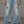 A tattooed model wears the light wash baggy jeans with grey trainers, gothic motifs on thighs and shins
