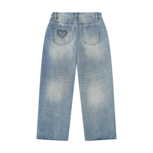 Back of the jeans laid flat, the barbed heart on one back pocket and the wash fading down each leg