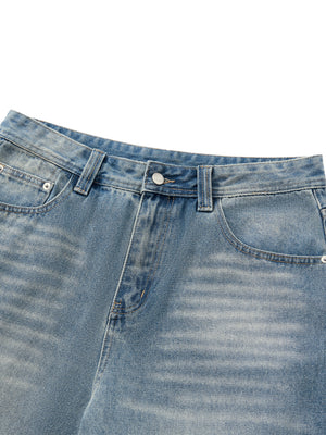 Close-up of the waistband, metal button and zip fly, with whiskering creased into the light blue denim
