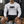 A man sits on a locker room bench in the white compression shirt and black shorts, front view