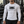 A man stands in a gym in the white long sleeve compression shirt, the knit tight over the arms