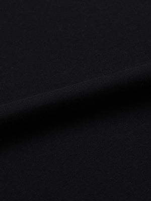 The black fabric laid flat and lit from the side to show the grain of the knit