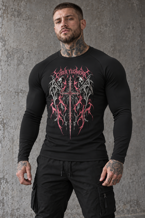 A tattooed man stands against concrete in the black shirt, the red skull and sword print on the chest
