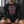 A man sits on a locker room bench in the black skull compression shirt and black shorts, front view