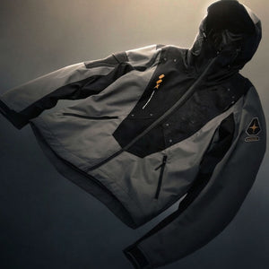 Grey hooded windbreaker shown flat with the hood raised, black shoulder panels and sleeve badge