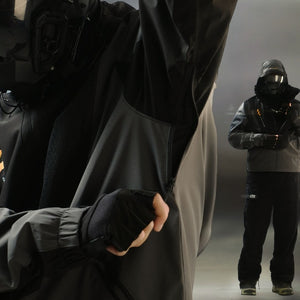 Arm raised to open the side zip vent, a second model standing in the full outfit behind him