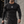 A man walks outside in the black compression shirt with cargo pants and a gym bag, front view