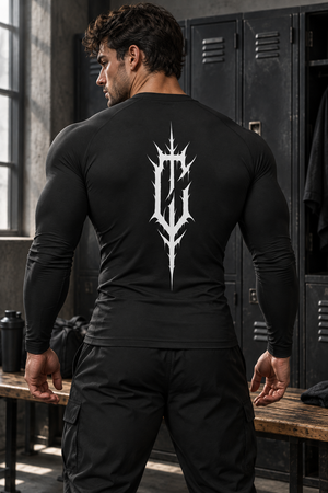 A muscular man in a locker room wears the black compression shirt, back view with the large spiked C print