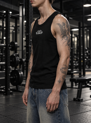 A model wears the black tank in a gym, the cut following the shoulder without pulling